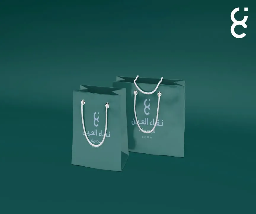 Carrier bags in two sizes, mark and Arabic wordmark in white on charcoal